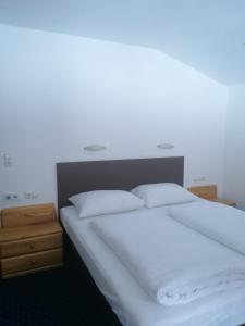 łóżko z białą pościelą i poduszkami w pokoju w obiekcie Appartment Danterhof w Mayrhofen