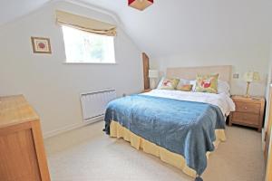 a bedroom with a bed with a blue blanket and a window at Grooms Cottage in Kent