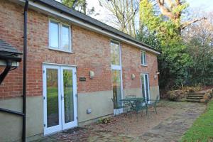 a brick house with a patio and a table at Grooms Cottage in Kent