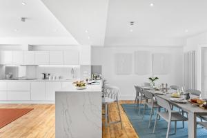 a white kitchen with a long table and chairs at HOE PARK HOUSE, Historic Gem, Accommodates 10, Parking, Pets Welcome, Prime Location Near Eateries, Bars & Stunning Coastal Views in Plymouth