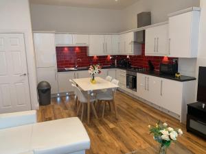 a kitchen with white cabinets and a white table and chairs at Spacious Apartment Close To City Centre in Leeds