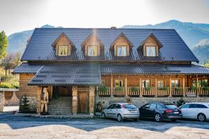 una casa de madera con coches aparcados frente a ella en Penzion Zbojník, en Terchová