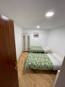 two beds in a small room with a door at Pradera de San Isidro in Madrid