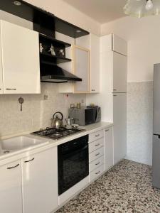 uma cozinha com armários brancos e um forno com placa de fogão em MAX and SEA parking em Sanremo