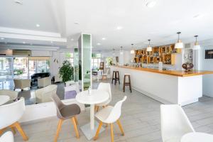 a restaurant with white tables and chairs and a bar at Hotel Koala in Kos