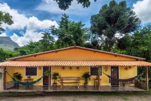 una casa amarilla con un banco delante en Pousada Aconchego en Vale do Capao