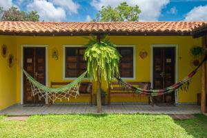 a yellow house with a hammock in front of it at Pousada Aconchego in Vale do Capao
