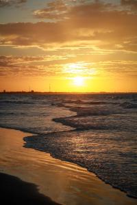 a sunset on a beach with the ocean at Aimberê Eco Resort Hotel in Coqueiro