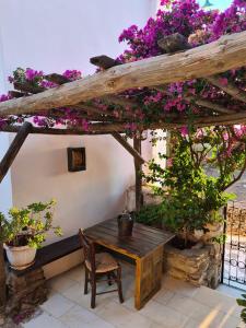 um pátio com uma mesa de madeira e flores roxas em Mili Art Home em Naxos Chora