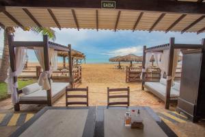 a beach with chairs and umbrellas on the beach at Aimberê Eco Resort Hotel in Coqueiro
