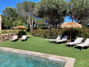 a group of lawn chairs and umbrellas next to a swimming pool at La Bastide du Soleil in Sainte-Maxime