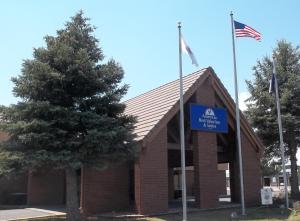 ein Schild vor einem Backsteingebäude mit amerikanischer Flagge in der Unterkunft Americas Best Value Inn & Suites Ft Collins E at I-25 in Fort Collins