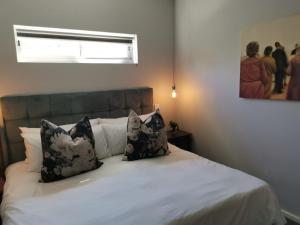 Schlafzimmer mit einem Bett mit weißer Bettwäsche und Kissen in der Unterkunft Oak Village in Stellenbosch