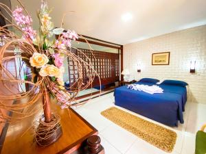 a bedroom with a blue bed and a table with flowers at Aimberê Eco Resort Hotel in Coqueiro