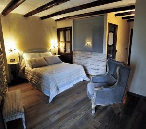 a bedroom with a bed and a blue chair at Hotel Boutique Real Posada De Liena y Restaurante Liena in Murillo de Gállego