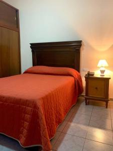 a bedroom with a bed with a red comforter and a table at Hotel San Fernando Ciudad Valles in Ciudad Valles
