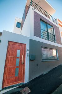 una casa con una puerta de madera en un lado en Apartamentos da Travessa en Praia da Vitória
