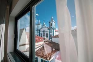 una ventana con vistas a una iglesia en Apartamentos da Travessa en Praia da Vitória
