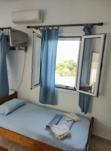Łóżko w małym pokoju z oknem w obiekcie studios.maria.anna w mieście Kamilari