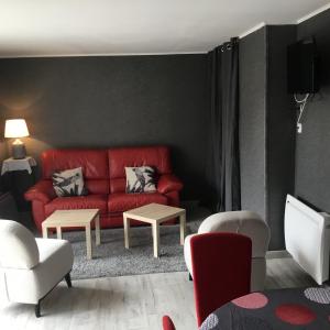 ein Wohnzimmer mit einem roten Sofa und Stühlen in der Unterkunft ALS locations calvet françoise in Jonzac