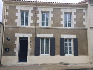 een oud bakstenen gebouw met een deur en ramen bij ALS locations calvet françoise in Jonzac