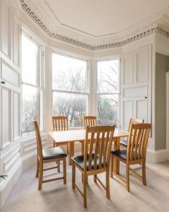 uma sala de jantar com mesa, cadeiras e janelas em Stunning 3 Bedroom Flat in Bruntsfield em Edimburgo