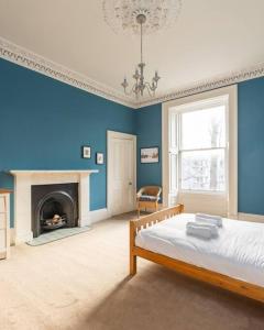 um quarto azul com uma cama e uma lareira em Stunning 3 Bedroom Flat in Bruntsfield em Edimburgo