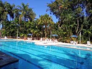 una gran piscina con sillas y sombrillas en RIVIERA SERVICE- Suíte Casal -113 en Bertioga
