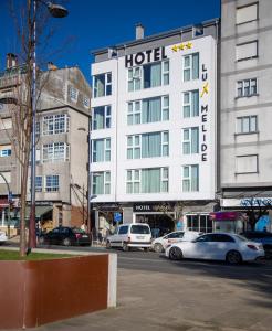 a hotel building with cars parked in front of it at Hotel Lux Melide in Melide