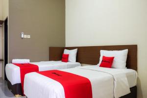 2 posti letto in una camera con lenzuola rosse e bianche di RedDoorz Syariah near Exit Tol Pemalang Comal 2 a Comal