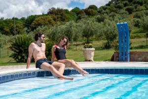 a man and a woman sitting in a swimming pool at Agriturismo La Banchella in Scarlino