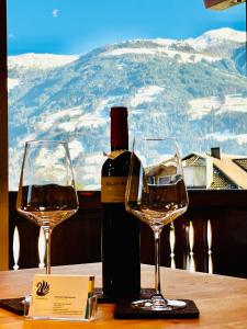 butelkę wina i dwa kieliszki wina na stole w obiekcie Royal Swan Appartement, Tirol w mieście Fügen