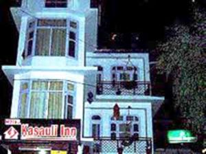 a white building with a sign in front of it at Kasauli Inn in Kasauli