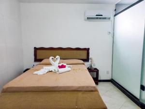 1 dormitorio con 1 cama con 2 cisnes hechos de toallas en Marlymar Apart Pousada en Natal