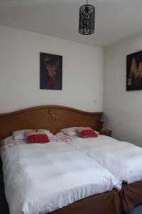 - une chambre avec un lit doté de draps blancs et d'oreillers rouges dans l'établissement Auberge du Pont de l'Alp, au Monêtier-les-Bains
