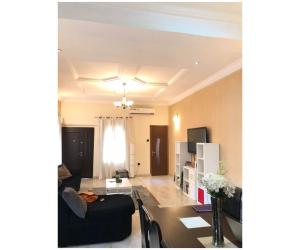 a living room with a black couch and a table at Amazing 4 Bedroom Duplex in Ikeja Allen Avenue in Ikeja