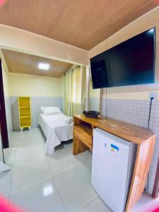 a room with a refrigerator and a tv on the wall at Casa Da Didda in Fernando de Noronha