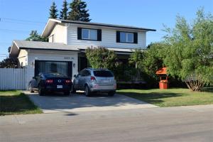 two cars parked in a parking lot in front of a house at The Dewberry Homestay B&B in Edmonton