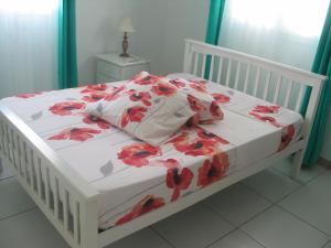 a white bed with a red flowered blanket on it at PETIT PARADIS in Quartier Morne la Valeur