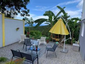 eine Terrasse mit Stühlen und einem gelben Sonnenschirm in der Unterkunft La villa ô plaisir in Deshaies