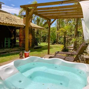 uma banheira de hidromassagem num quintal com uma pérgola em Morada Amazona na Praia do Rosa