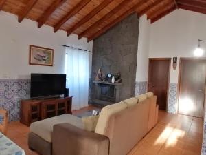 a living room with a couch and a television at A Casa da Formosinha in Madalena