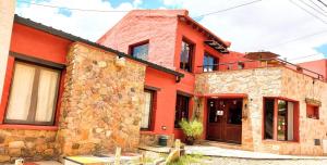 una casa de ladrillo rojo con un edificio de piedra en Munay Humahuaca en Humahuaca