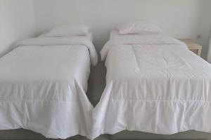 - deux lits blancs assis l'un à côté de l'autre dans l'établissement RedDoorz near Pantai Madasari Pangandaran, à Bulakbenda