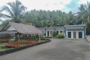 a building with chairs and palm trees in the background at RedDoorz near Pantai Madasari Pangandaran in Bulakbenda