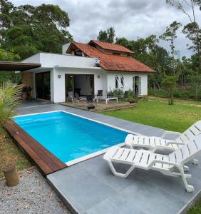 una piscina con 2 sillas y una casa en Morada de Neide, en Garopaba