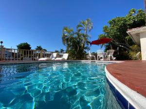 a swimming pool with chairs and an umbrella at Villa-Coral-Ridge in Fort Lauderdale