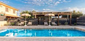 einen Pool mit Stühlen und Sonnenschirmen neben einem Haus in der Unterkunft Albergo Luisss in Marina di Grosseto