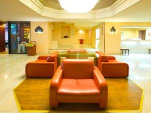 a lobby with three orange chairs and a glass table at Hotel Ascent Hamamatsu in Hamamatsu