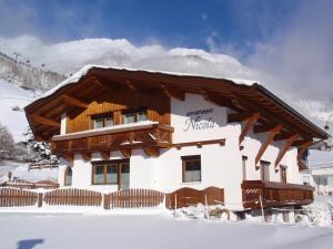 a house in the snow with a mountain in the background at Appartement Nicola in Sölden